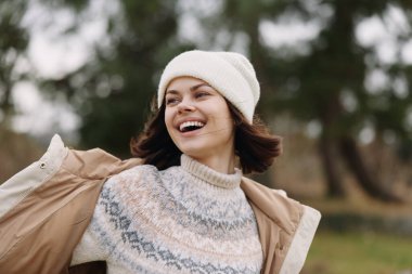 Örgü ve palto giyen kadın açık hava parkı havasını, neşe ve özgürlük ifadesini, sonbahar modasını seviyor.
