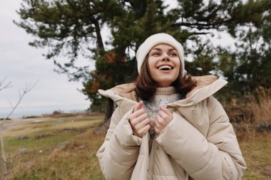 Açık hava portresi, kışın giydiği, ceketi ve örgü şapkası olan, engebeli bir sahil kenarında esinti ve açık manzaranın tadını çıkaran bir kadın..