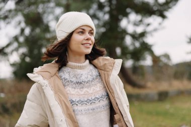 Serin bir açık hava ortamında örgü süveter ve bere giyen, rahat bir dış giysiyi ve kırsal alanda rahat bir havayı vurgulayan bir kadının sıradan portresi..