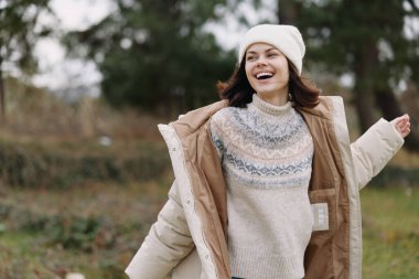 Örgü ören süveter ve bereli, yumuşak bir ışıkla doğal bir tarlada duran, tasasız bir açık hava keyfi ve konforu taşıyan, gülümseyen bir kadının sıradan portresi..