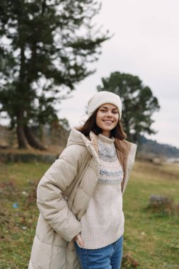 Şişkin ceketli, rahat örgü ören neşeli genç bir bayanın serin kırsal havanın tadını çıkardığı sıradan bir moda sahnesi..
