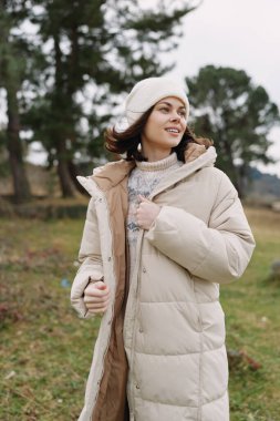 Sıcak ceketli sıradan bir açık hava modası, kışlık hazır görünüş kabarık bir ceket, örgü ve bere, dingin park dekorasyonu ve fotoğraflar için temiz hava..