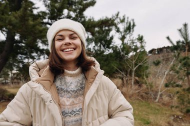 Sıcak bir palto ve bere giyen neşeli bir kadının portresi doğal bir ortamda gevşemiş bir ruh hali ve kışın giydiği kışın serin dokuları yakalıyor..