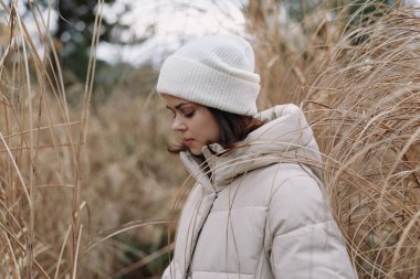 Sıcak bir palto giymiş bir kadının açık hava portresi ve rüzgarlı bir tarlada bereyle sakin bir kış havasını yansıtıyor..