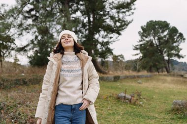Serin bir günde rahat stil, rahatlık ve temiz hava yakalayan, örgü kazak ve uzun ceket giyen bir kadının açık hava portresi..