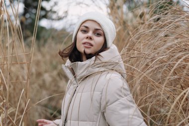 Uzun otların arasında kabarık bir palto ve bere giyen şık bir kadının olduğu açık hava sahnesi, yaşam tarzını, sıcaklığını ve huzurlu doğal ortamını ön plana çıkarıyor..