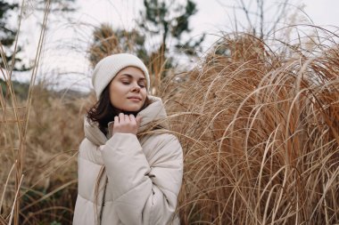 Rahat bir eşarp ve bereli bir kadının portresi otlaktan bir tarlada sergilenen moda, sıcak ve sakin bir ortam.