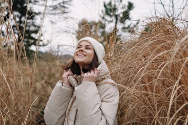 Açık havada kabarık ceketli ve örgü şapkalı bir kadının portresi. Etrafı güneş ışığında çimlerle çevrili. Soğuk bir çayır, sakin bir ifade..