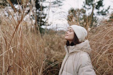 Doldurulmuş bir palto giyen ve soğuk bir tarlada örgü ören bir kadının portresi, sakin mevsimsel güzelliği ve doğadaki sakin havayı yakalıyor..