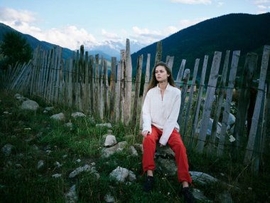 Ahşap çitli, dağ manzaralı, sakin manzaralı, sakin esintili, yeşillikli, düşünceli bir poz. Yalnızlığı ve doğayla bağlantıyı aktarıyor.