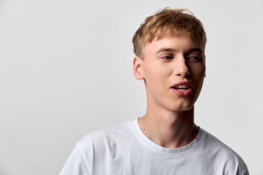 Düz bir arkaplandan önce yumuşak bakışlı beyaz tişörtlü sıradan bir manken, moda, sağIık ve gençlik hayat tarzı hikayeleri için çok yönlü.