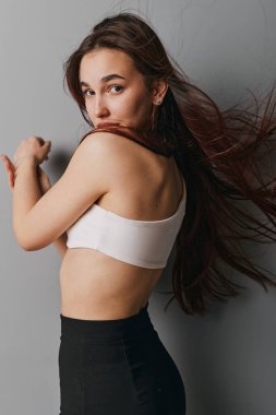 Beyaz tarla desenli saçlarıyla, siyah eteğiyle çıplak sırtında poz veren ve portre tarzında gri arkaplanda yoğun bakışları olan kadın model..