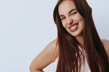 Uzun düz saçlı, gülümseyen ve beyaz arka planda poz veren genç bir kadın. Doğal makyajlı bir kadın portresi ve yaşam tarzı ya da güzellik anlayışı için neşeli bir ruh hali..