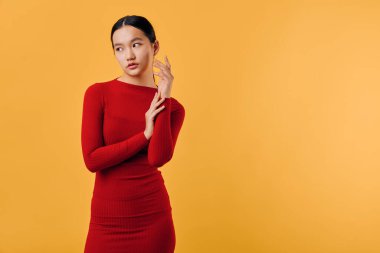 Kırmızı elbiseli genç bir kadın portresi. Kolları katlanmış ve düşünceli bir görünümü var. Turuncu arka planda duruyor..