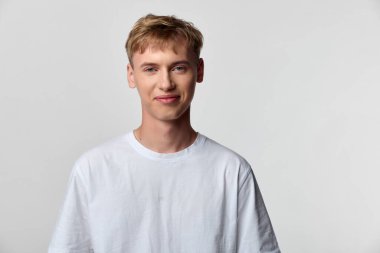 Beyaz tişörtlü sıradan bir adamın günlük yaşam tarzı, moda temaları ve ticari hisse senedi kullanımı için ideal bir arkaplan karşısındaki stüdyo fotoğrafı.