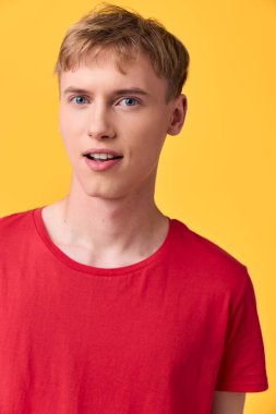 Parlak sarı arka planı olan kırmızı bir gömlek giyen sıradan bir erkek manken. Stüdyo, açık ten rengini ve reklam için çağdaş moda atmosferini ön plana çıkarıyor.