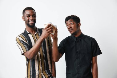 Koyu tenli genç siyahi erkekler kahve fincanlarını paylaşıyor ve beyaz arka planda arkadaşlığın ve günlük hayatın tadını çıkarıyorlar..