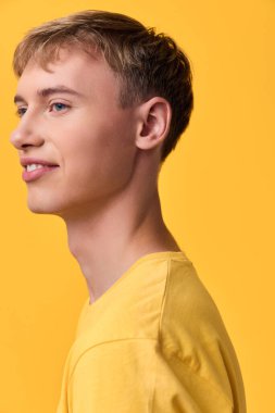 Sarı gömlekli genç bir adamın enerjik stüdyo görüntüsü, güneşli arka plan, cesur renk koordinasyonu, günlük kıyafet, kendine güvenen duruş, modern moda fotoğrafçılığı neşeli ruh hali, neşeli ve neşeli.