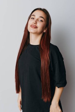 Siyah kıyafetli, uzun kahverengi saçlı, sakin bir yüz ifadesi ve hafif aksesuar ve hafif ışıklandırma sergileyen genç bir kadın..