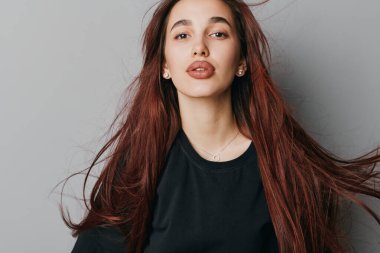 Kendine güveni tam bir genç kadın portresi, dalgalı kızıl saçlı, sade arka planda günlük siyah giyimli, yaşam tarzı, tarzı ve güzellik içeriği için..