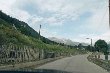 Dağ yolu çiti köyü gökyüzü doğa boş şerit ahşap çit yeşil kenar ve uzak bulutlu zirveler