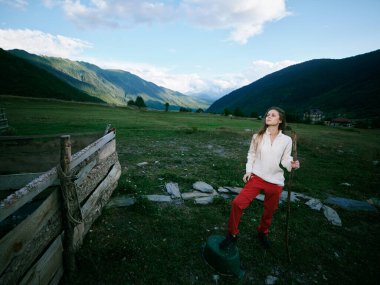 Yürüyüş, dağlar, manzara, doğa, yürüyüş, vadi, manzara, macera, bir kadın çim ve çit rayları arasında yürüyüş direğiyle ayakta duruyor, geniş vadi ve açık gökyüzünün tadını çıkarıyor.