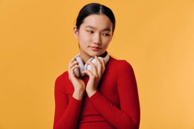 Kırmızı başlıklı kadının portresi, parmakları turuncu arka planda, sakin yüzünü ve doğal makyajını gösteren, düzgün saçlı, yaşam tarzı ve modaya uygun şekilde bağlanmış..