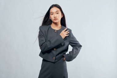 Kendine güvenen, uzun saçlı, resmi koyu gri ceket ve etek giymiş, profesyonel veya tarz teması için göğsü açık poz veren genç bir kadının portresi..