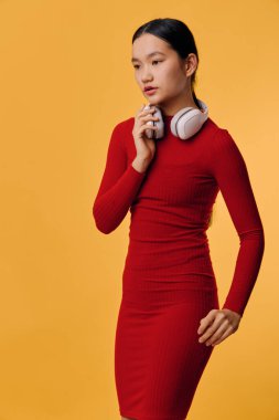 Beyaz kulaklıklar ve mobil cihazlarla dikilen kırmızı elbiseli kadın portresi. Modern tarz, dijital yaşam tarzı, iletişim, müzik ve teknoloji kavramı.