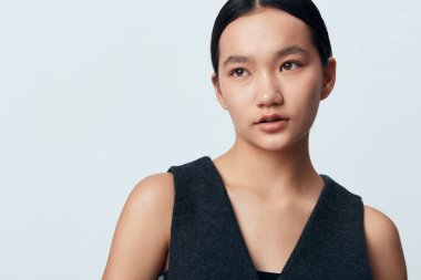 Uzun saçlı, kolsuz bluzlu genç bir kadının portresi, temiz arka planda sakin bir yüz, doğal güzelliği ve açık tenli basit bir stili olan,.