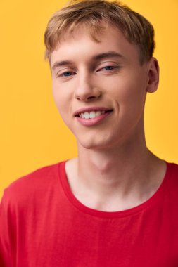 Genç adam, gülümseyen, sıradan kırmızı gömlekli, parlak arkaplan, rahat görünüm, temiz kompozisyon ve sıcak hava, markalaşma, pazarlama ve yaşam tarzı kampanyaları için ideal