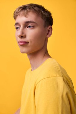 Tek renkli bir ortamda parlak sarı giyimli erkek modeli, minimalizm, güven, modern sokak giyimi atmosferi, hafif ışıklandırma ve editoryal stoklar için kusursuz kompozisyon.