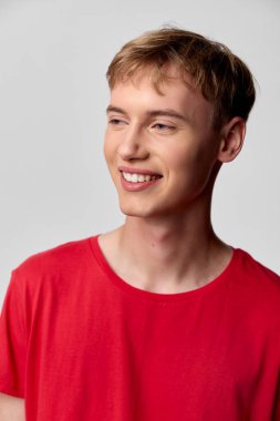 Cesur kırmızı tişört giyen neşeli genç adam, rahat duruş, sıcak ifade ve rahat görünüm, markalaşma, yaşam tarzı ve ürün dergileri için mükemmel, arkadaş canlısı, davetkar bir atmosfere ihtiyacı var..