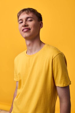 Stüdyo ortamında parlak sarı bir gömlek giyen genç, neşeli bir enerji, moda anlayışı ve cana yakın, arkadaş canlısı bir tutum sergiliyor..