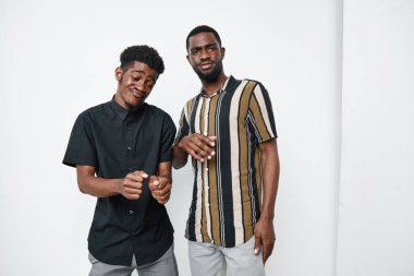 Siyah çizgili ve siyah gömlekler giyen, parlak stüdyoda mutluluk ve dostluğu ifade eden, koyu tenli iki Afrikalı adamın portresi..