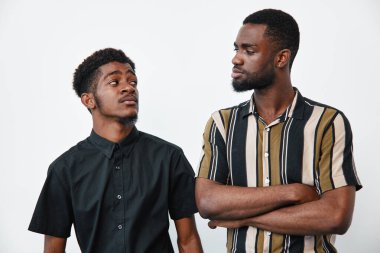 Siyah çizgili ve siyah tişörtlü Afro-Amerikalı erkekler birbirlerine bakıyorlar. Sade beyaz arka planda gündelik ve resmi tarzı olan genç siyah erkekler..