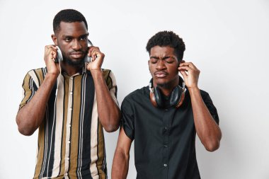Koyu tenli Afrikalı erkekler kulaklıkla müzik dinliyor. Çizgili gömlekli bir adam kulaklık takıyor, diğeri siyah gömlekli, gözleri kapalı, sesten zevk alıyor..