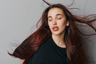 Kadın portresi dalgalı saçlar ve gözleri kapalı rahat bir ifade, moda çekimlerinde doğal güzelliği ve saç hareketini sergiliyor..