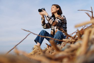 Dış mekan fotoğrafçısının portresi. Uzun çimenlerin arasında. Kamera gündelik giysiler, doğal ışık ve sakin kırsal atmosfer.