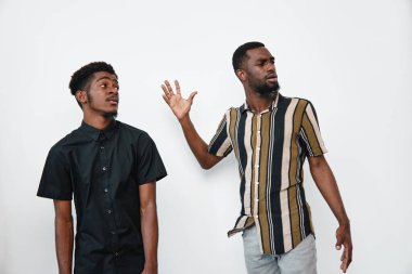 Siyah elbiseli, siyah gömlekli ve çizgili gömlekli Afro-Amerikalı erkekler, stüdyo ortamında beyaz arka planda el hareketleriyle iletişim kuruyorlar..