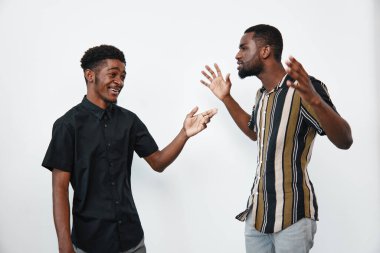Esmer tenli Afro-Amerikalı erkekler günlük kıyafetlerle konuşup gülüyorlar. Arkadaşlık, iletişim ve olumlu duygular beyaz arka planlı parlak bir stüdyo ortamında.