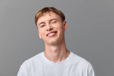 Dost canlısı sırıtış ve yumuşak stüdyo ışıklandırmasına sahip sıradan bir erkek model, reklam, markalaşma, eğitim ve dijital medya ve kampanyalarda yaşam tarzı içeriği için basit temiz bir arka plan.