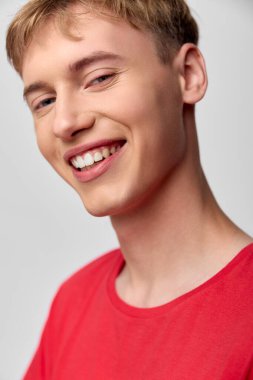 Kırmızı gömlekli neşeli genç adam, neşeli yüz ifadesi, yakın kompozisyon, minimum ayar, yumuşak ışıklandırma, temiz fon, hoş geldin havası, modern ve rahat