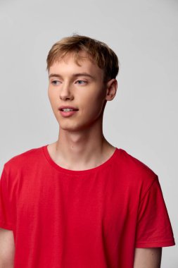 Temiz bir stüdyo odasında kırmızı gömlek giyen, özgüvenli, arkadaş canlısı bir görünüm ve modern moda atmosferi sunan genç bir adamın sıradan bir resmi.