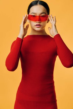 Kırmızı kazaklı, modern kırmızı vizörlü genç Asyalı kadın sarıya karşı. Moda modelinin yaratıcı konsept için minimalist stili ve koyu renk karşıtlığını gösteren stüdyo fotoğrafı.