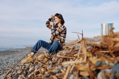 Sahilde, rahat bir yaratıcı anda, dalgaları, ışığı ve akıntıyı belgelemek için objektiften odaklanan sıradan bir fotoğrafçı.
