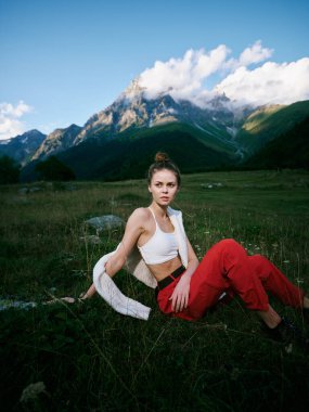 Çayırda rahat bir poz, arka planda dağlar, fotoğrafçılık ve seyahat için doğa, açık hava yaşam tarzının vurgulanması, manzaralı manzara ve temiz hava