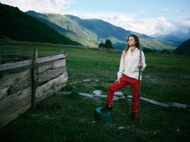 Dağların altındaki bir tarlada bir kadınla kırsal alan manzarası, açık hava manzarası, bir personelle yürüyüş duruşu, kırsal alan, canlı doğa ve geniş açık atmosfer.
