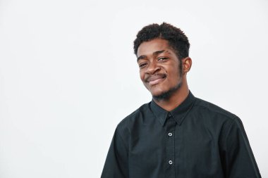Siyah tişörtlü, siyah tenli, beyaz arka planda poz veren kendinden emin genç bir zenci. Kısa saçlı Afrikalı etnik erkek ve stüdyo resminde rahat bir ifade..