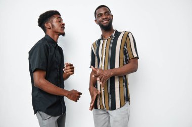 Koyu tenli, günlük kıyafetlerle sohbet eden ve gülümseyen genç siyahi adamlar. Beyaz arka plan stüdyosunda Afrika etnik kökeni, sosyal etkileşim ve arkadaşlık.